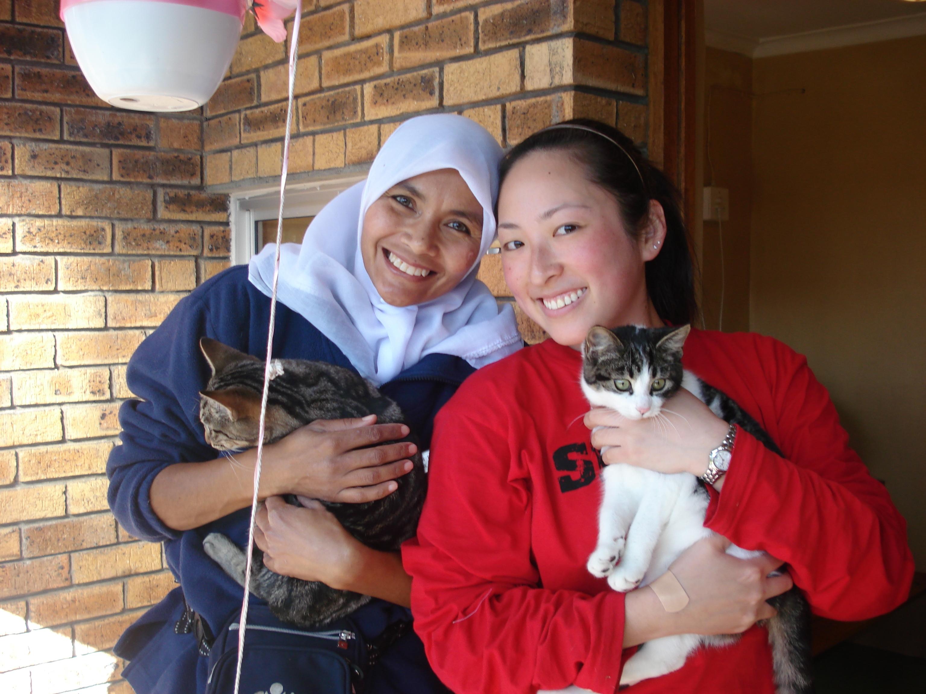 Animal Care staff holding a cat alongside a volunteer with animals in South Africa Cats being held and cared for by volunteers who work with animals in South Africa